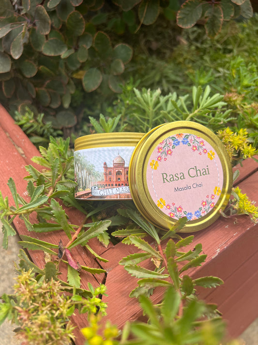 Open tin of masala chai sitting in grass, label says "Rasa Chai"