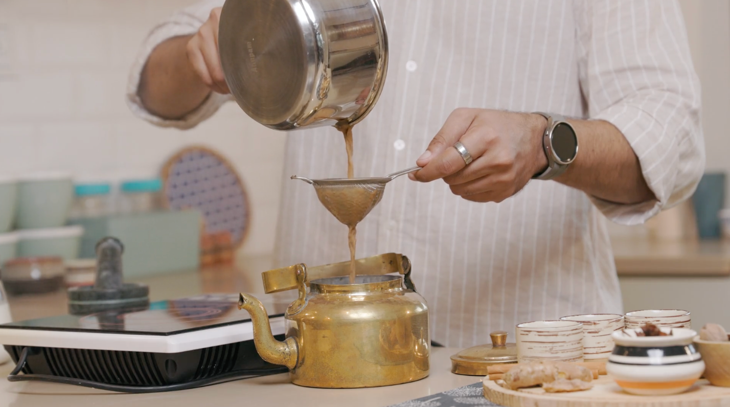 Load video: A video tutorial with aesthetic background music and ASMR sounds showing the process of making Indian Masala Chai. A faceless hand boils water, adds the Rasa Chai Masala Chai mix, adds milk and sugar, then pours through a strainer into a tea cup.