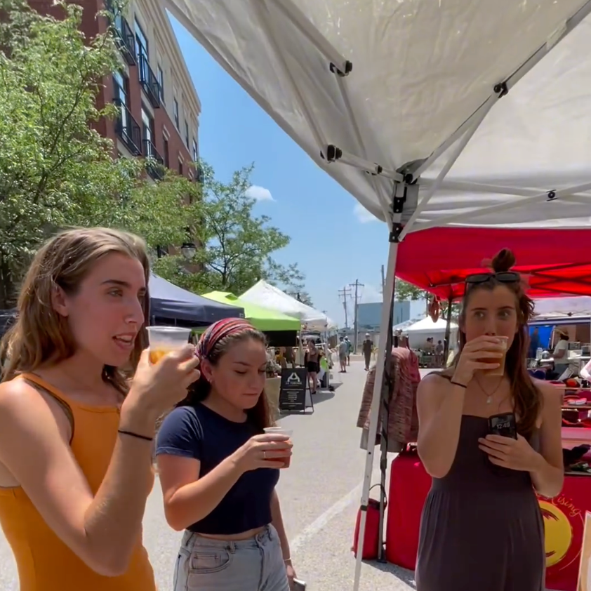 Photo of three women drinking cups of chai at a farmers market